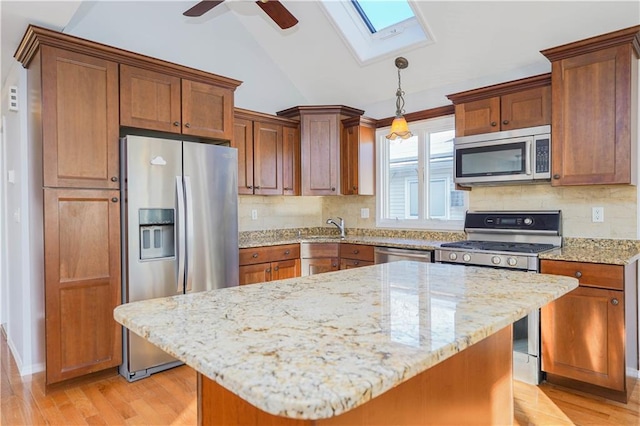 kitchen with light wood-style flooring, a sink, vaulted ceiling, appliances with stainless steel finishes, and light stone countertops