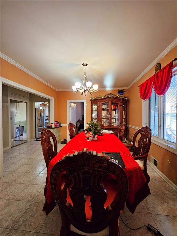 dining space featuring light tile patterned flooring, an inviting chandelier, and crown molding