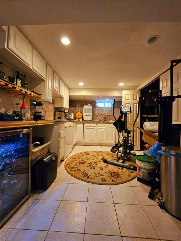 interior space with sink, beverage cooler, white cabinetry, and light tile patterned floors