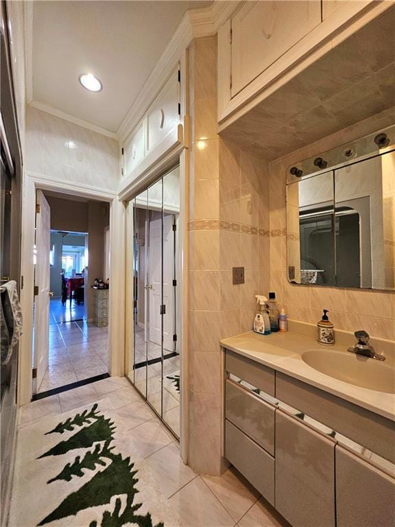 bathroom with tile walls, tile patterned flooring, crown molding, and vanity