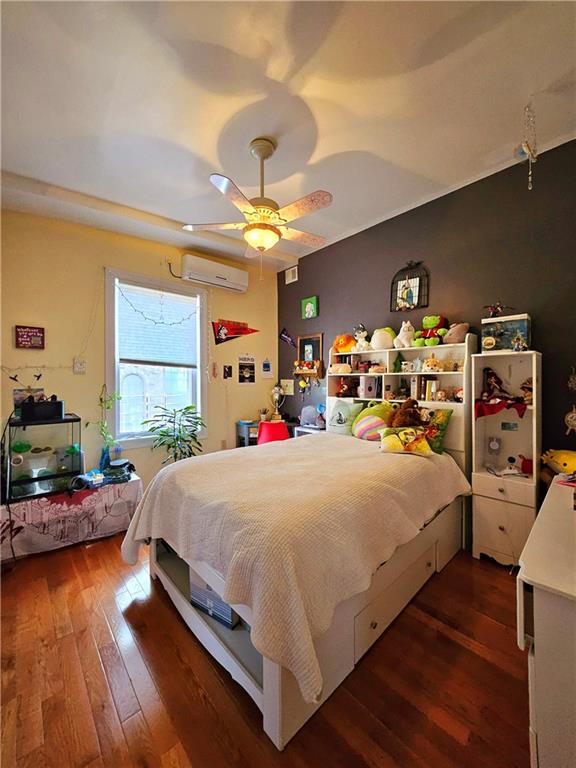 bedroom featuring ceiling fan, dark hardwood / wood-style flooring, and a wall mounted air conditioner