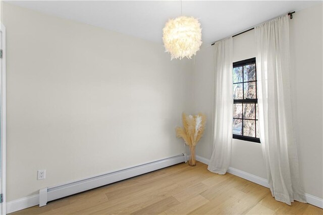 unfurnished room featuring light hardwood / wood-style flooring, a notable chandelier, a wealth of natural light, and a baseboard radiator