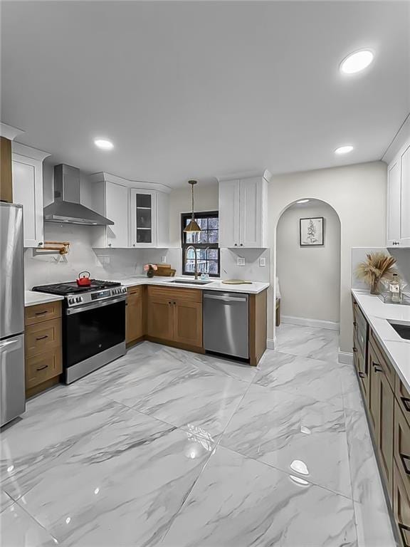 kitchen with appliances with stainless steel finishes, wall chimney exhaust hood, and white cabinets