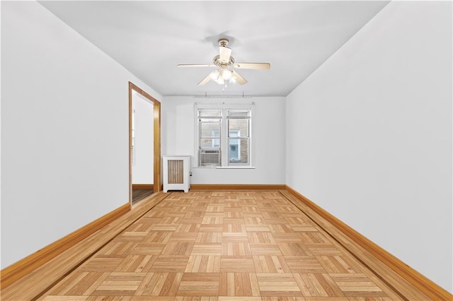 spare room with cooling unit, ceiling fan, radiator heating unit, and light parquet floors