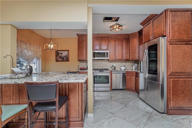 kitchen with appliances with stainless steel finishes, tasteful backsplash, a kitchen breakfast bar, hanging light fixtures, and light stone counters