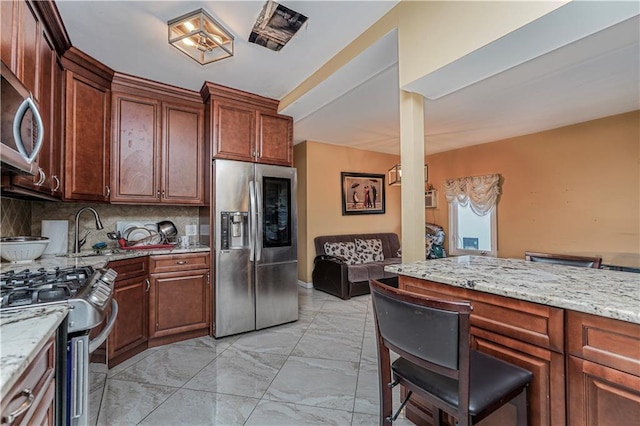 kitchen with stainless steel appliances, light stone countertops, sink, and decorative backsplash