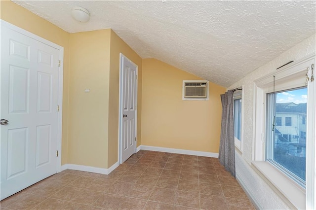 hall featuring light tile patterned floors, a textured ceiling, vaulted ceiling, and a wall mounted AC