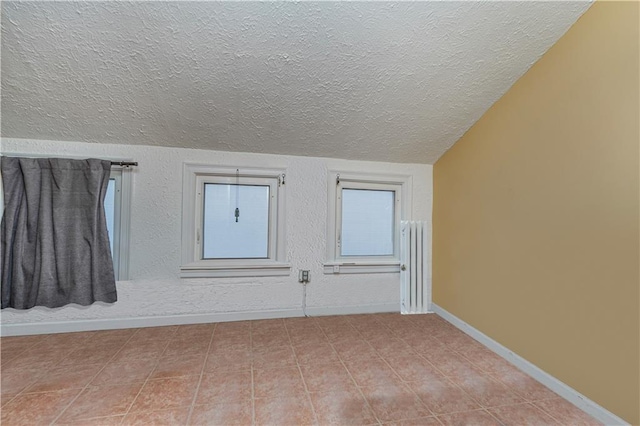 empty room with vaulted ceiling and a textured ceiling