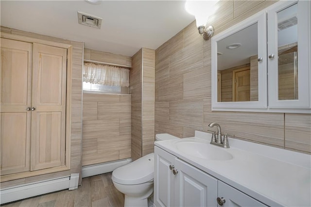 bathroom featuring a baseboard radiator, vanity, toilet, and tile walls