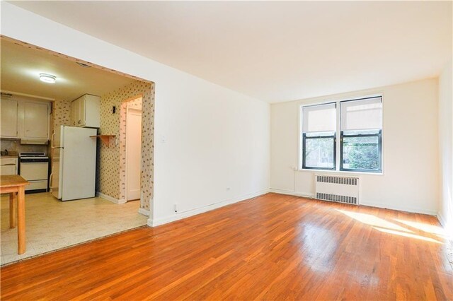 spare room featuring radiator and light wood-type flooring