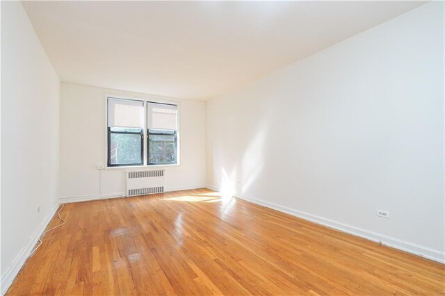 spare room with light wood-type flooring and radiator heating unit