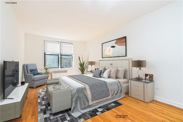 bedroom with radiator heating unit and light hardwood / wood-style flooring