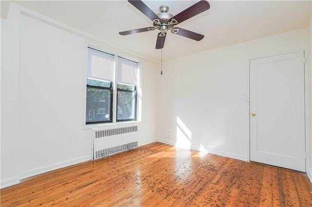 spare room with ceiling fan, radiator, and hardwood / wood-style flooring