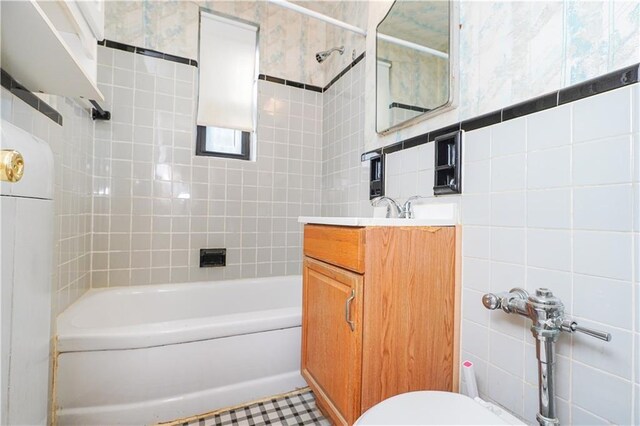 full bathroom with toilet, vanity, tile walls, and tiled shower / bath combo