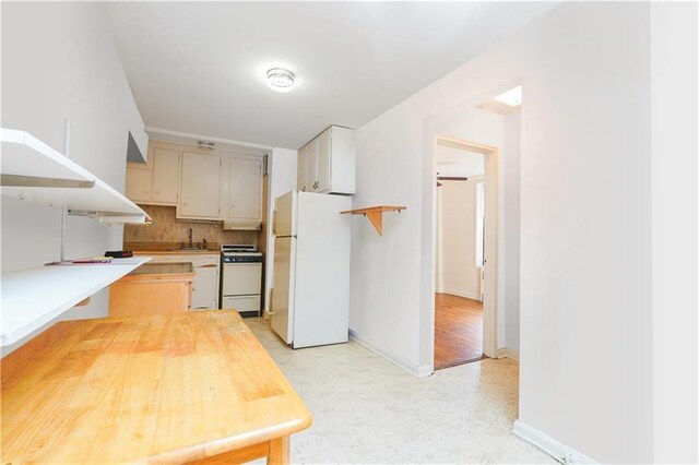 kitchen with decorative backsplash, sink, white refrigerator, and range