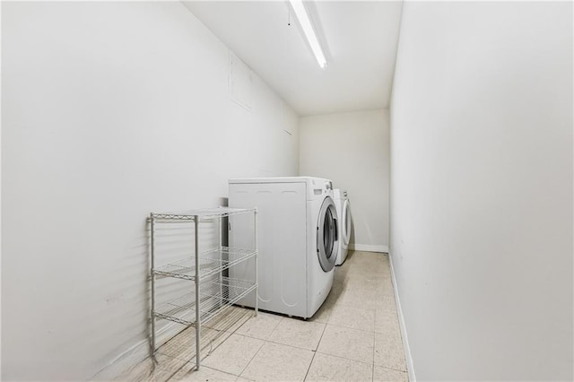 laundry area with light tile patterned floors, separate washer and dryer, baseboards, and laundry area
