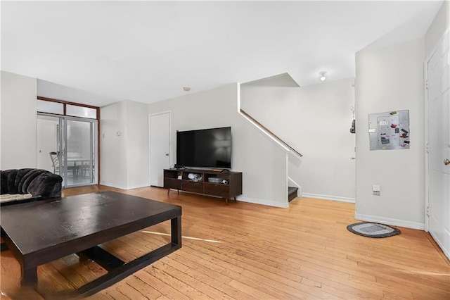 living area with light wood finished floors, stairway, and baseboards