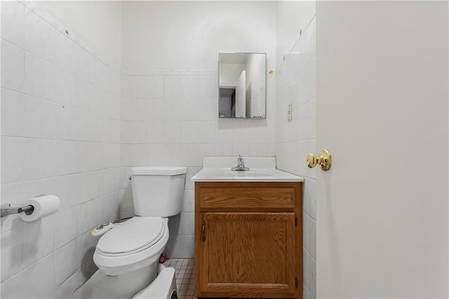 half bath with tile walls, vanity, and toilet