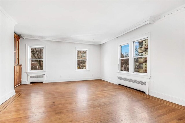 spare room featuring radiator heating unit, ornamental molding, and light hardwood / wood-style flooring