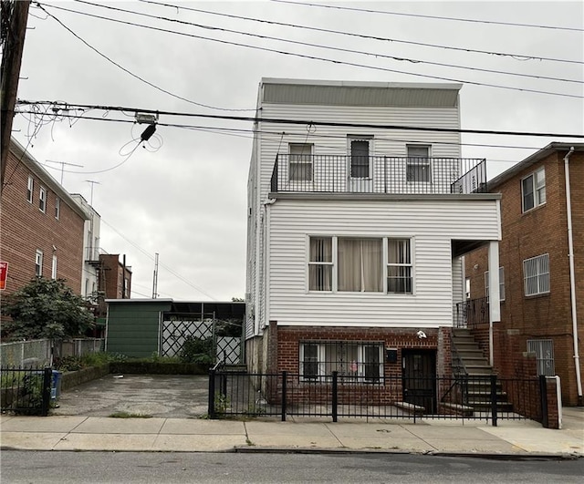 view of front facade featuring stairway, brick siding, and a fenced front yard