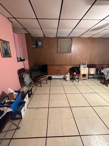 6311 13th Ave, Brooklyn, NY 11219 - finished below grade area featuring a paneled ceiling, wooden walls, and light tile patterned floors