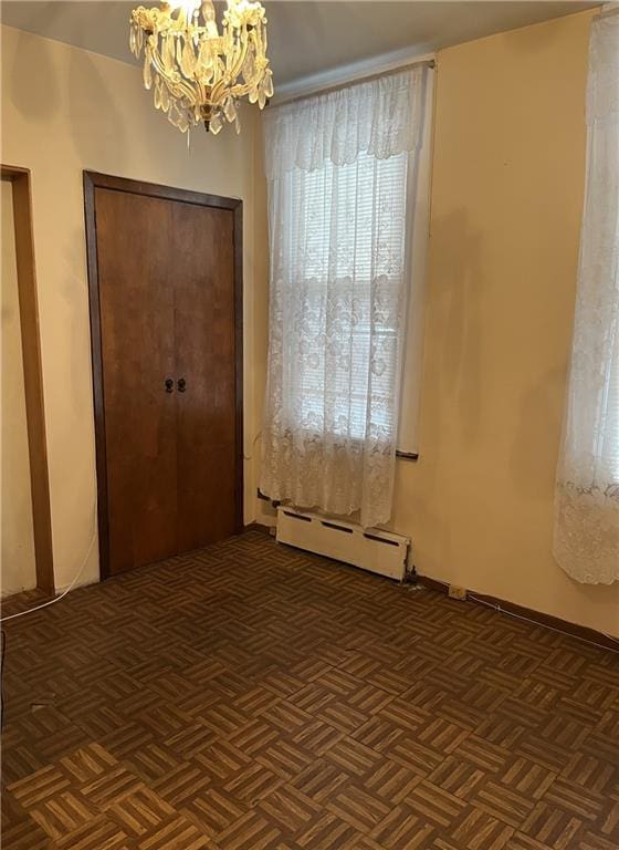 interior space featuring a baseboard heating unit, an inviting chandelier, and dark parquet floors