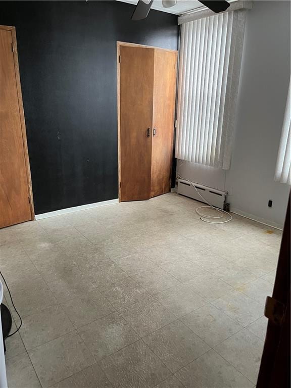 unfurnished room featuring a baseboard radiator, baseboards, light floors, and a ceiling fan