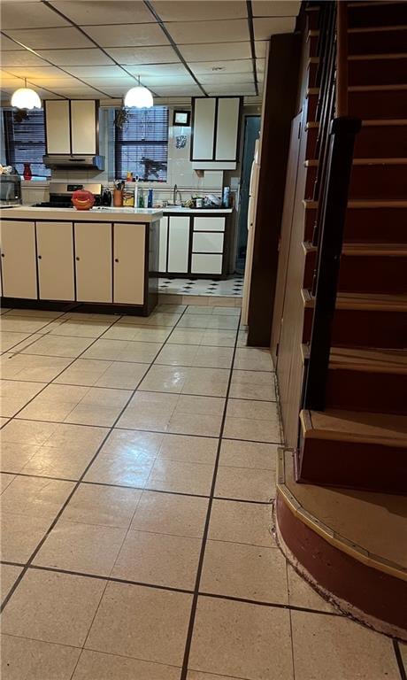 kitchen featuring light tile patterned floors and a drop ceiling