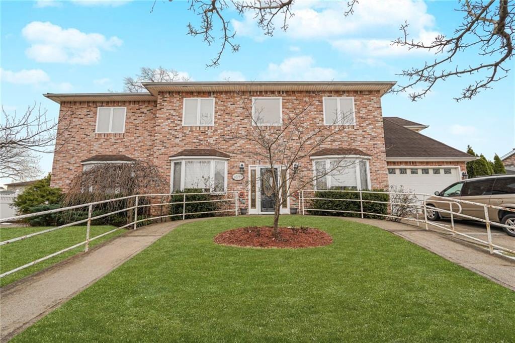 1044 Edgegrove Ave, Staten Island, NY 10309 - colonial home featuring a garage, driveway, a front lawn, and brick siding