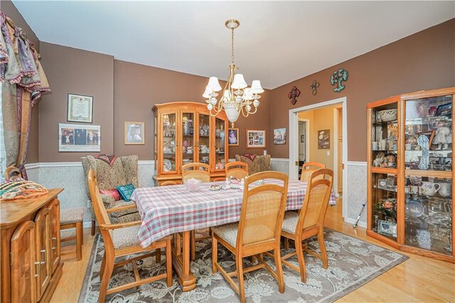 dining area with light hardwood / wood-style floors and a notable chandelier