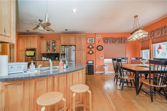 kitchen featuring light hardwood / wood-style floors, ceiling fan, stainless steel appliances, decorative light fixtures, and sink