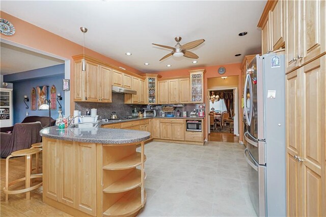 kitchen with decorative light fixtures, kitchen peninsula, a breakfast bar area, stainless steel appliances, and light brown cabinetry