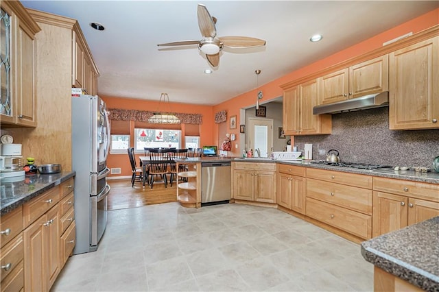 kitchen featuring kitchen peninsula, ceiling fan, stainless steel appliances, decorative backsplash, and decorative light fixtures