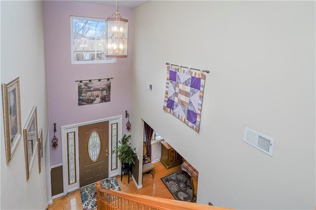 entrance foyer featuring light parquet floors, a chandelier, and a towering ceiling