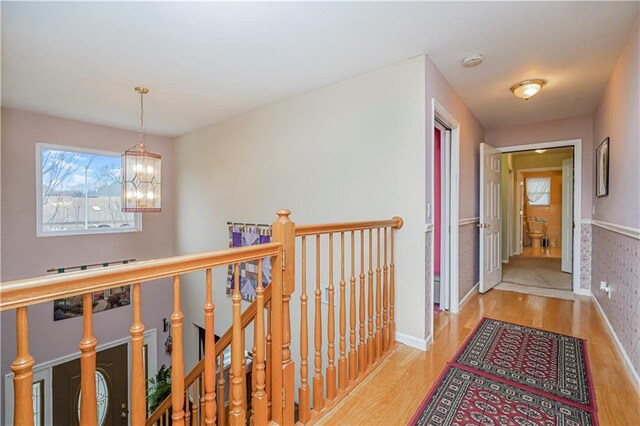 corridor with an inviting chandelier and light hardwood / wood-style flooring