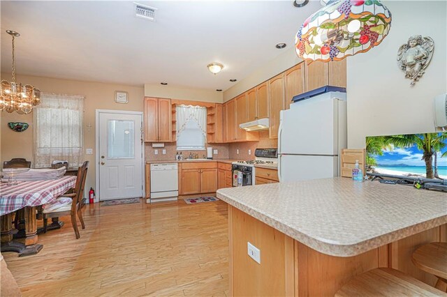 kitchen featuring kitchen peninsula, decorative backsplash, decorative light fixtures, light wood-type flooring, and white appliances