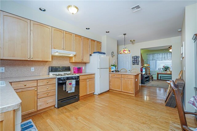 kitchen featuring decorative light fixtures, light brown cabinets, white fridge, and gas stove