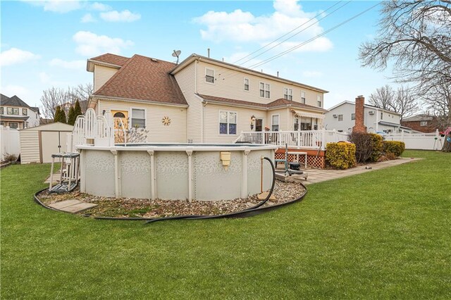 back of property with a lawn, a pool side deck, and a storage shed