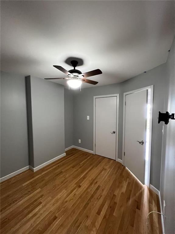 unfurnished bedroom with a ceiling fan, wood finished floors, and baseboards