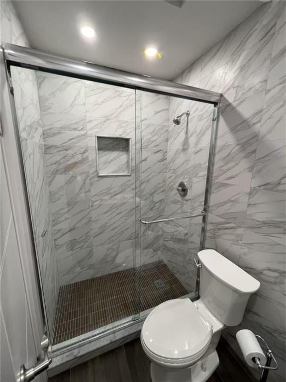 bathroom featuring a shower stall, toilet, and wood finished floors