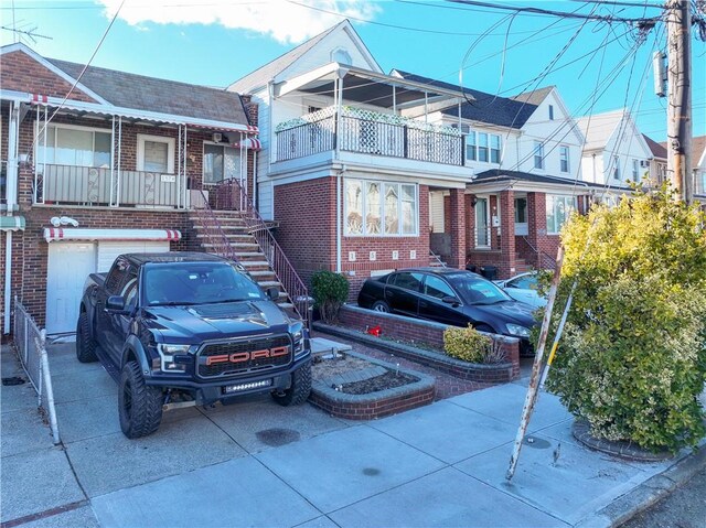 view of front of house featuring brick siding, concrete driveway, and stairs