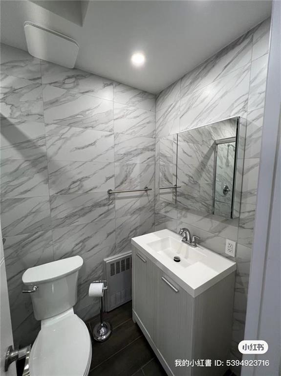 1574 E 66th St, Brooklyn, NY 11234 - bathroom with radiator heating unit, toilet, vanity, and tile walls