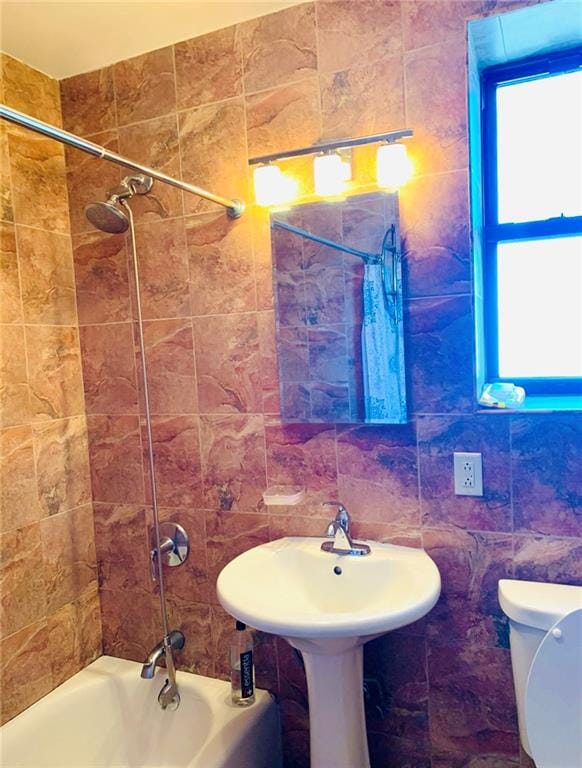 bathroom featuring toilet, shower / tub combination, and tile walls