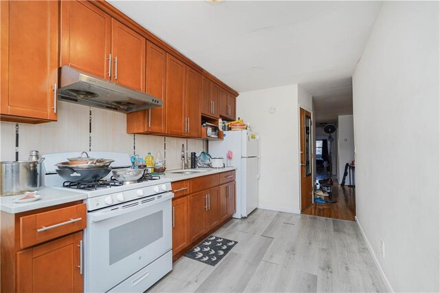 kitchen featuring sink, white appliances, and light wood-type flooring