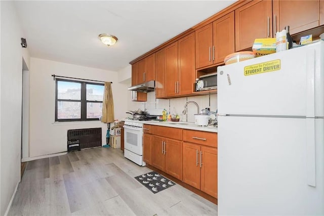 kitchen featuring heating unit, sink, white appliances, and light hardwood / wood-style floors