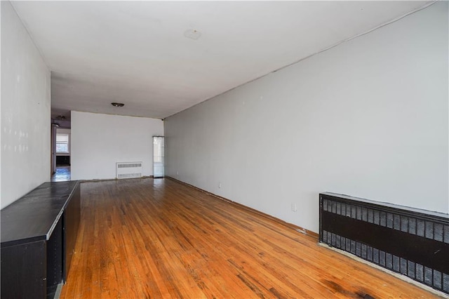 unfurnished living room with hardwood / wood-style flooring and radiator heating unit