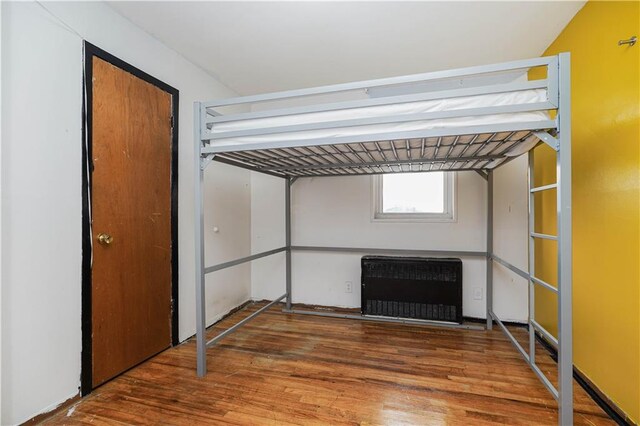 unfurnished bedroom with hardwood / wood-style floors and radiator heating unit