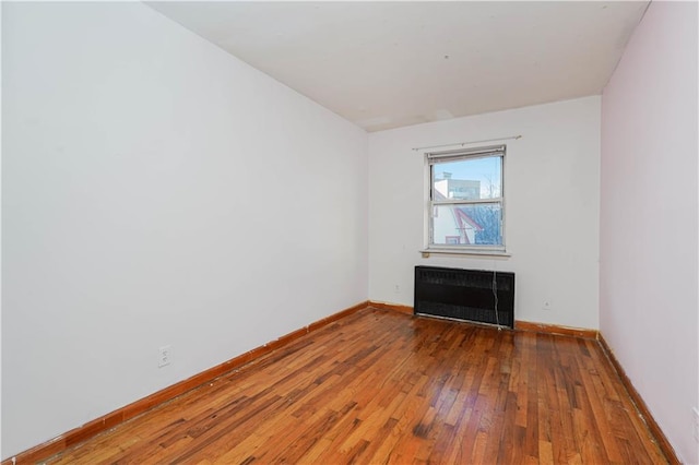 empty room featuring a fireplace, radiator, and hardwood / wood-style floors