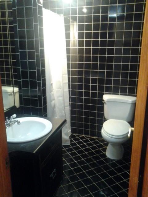 bathroom featuring toilet, tile walls, vanity, curtained shower, and tile patterned flooring