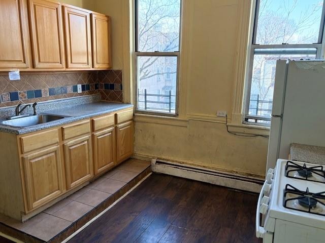 kitchen featuring a baseboard heating unit, plenty of natural light, sink, and white appliances